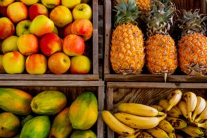 Exportação de Frutas: uma oportunidade. Imagem: Magda Ehlers/Pexels. Banada, mamão, abacaxi dentro de caixas de mandeira numa venda.