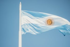 Bandeira Argentina com um céu azul ao fundo. Exportações para a Argentina: vantagens e desafios